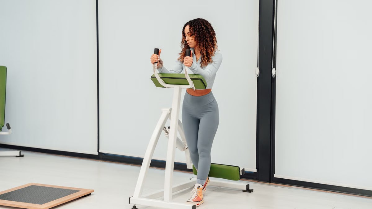 A young woman exercises on fitness equipment in a modern indoor gym setting, embracing a healthy lifestyle.